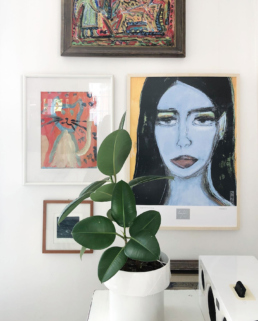 A small gallery wall with an art poster of a black-haired woman with green eyes