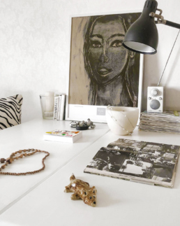 Art poster of a woman leaning towards a wall on top of a desk