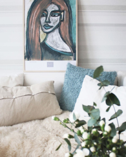 Art poster above a sofa portraying a woman with reddish hair