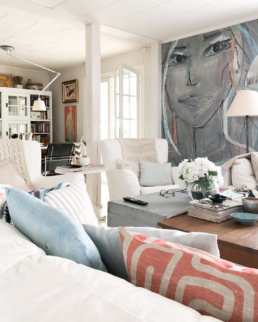 View of an eclectic livingroom with a huge art wall portraying a woman